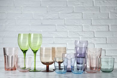 Photo of Many different glasses on white marble table against brick wall. Space for text