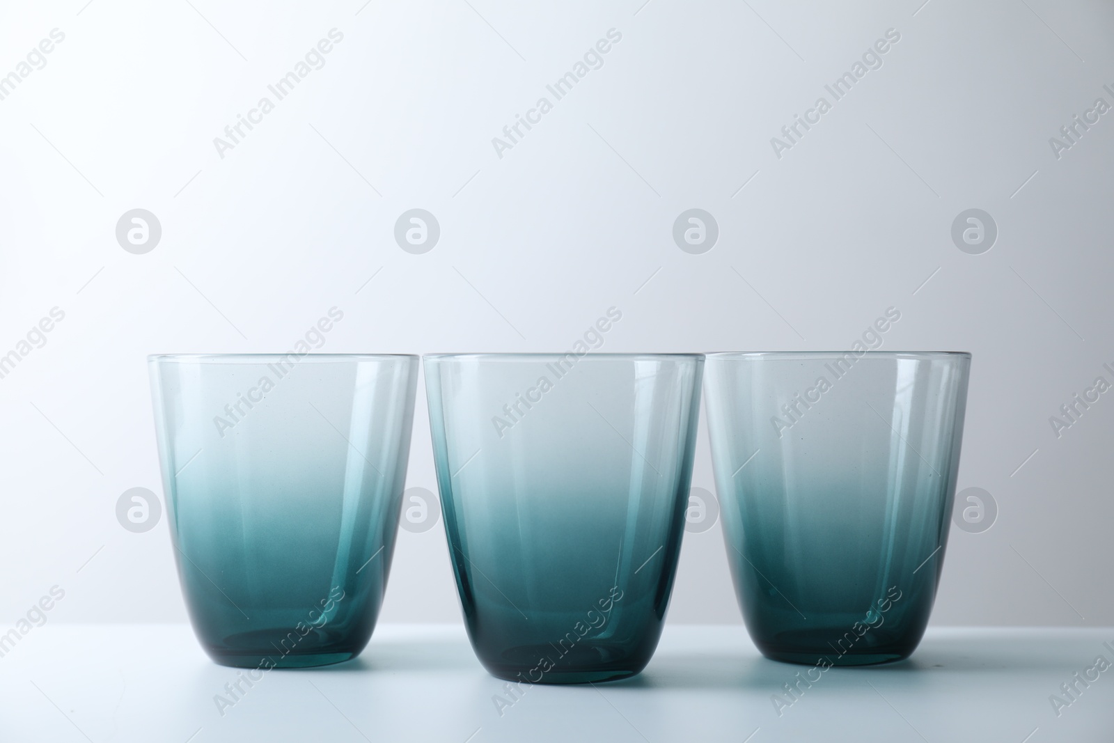 Photo of Three empty clean glasses on light background