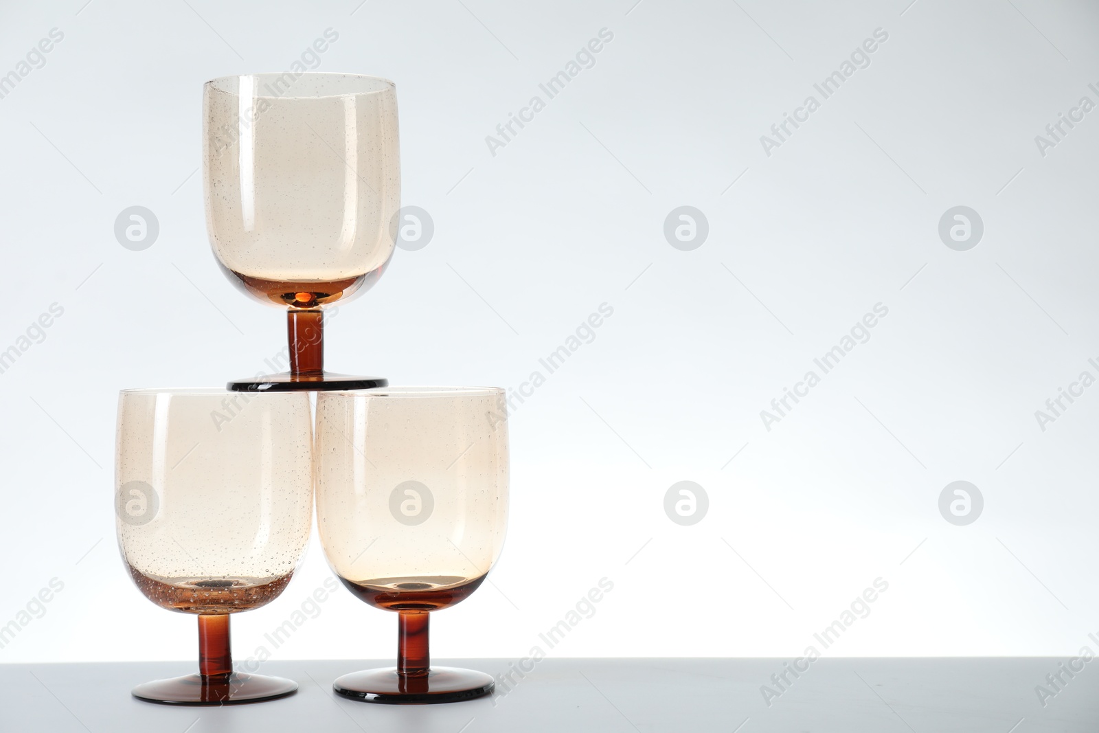 Photo of Three empty clean glasses on light background. Space for text