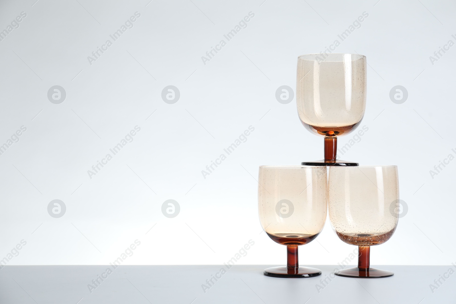 Photo of Three empty clean glasses on light background. Space for text