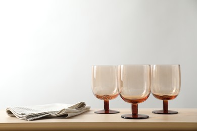 Photo of Three empty clean glasses and towel on wooden table. Space for text