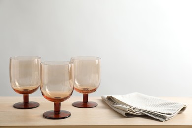 Photo of Three empty clean glasses and towel on wooden table. Space for text