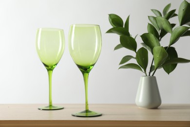 Photo of Two empty clean glasses and vase with leaves on wooden table