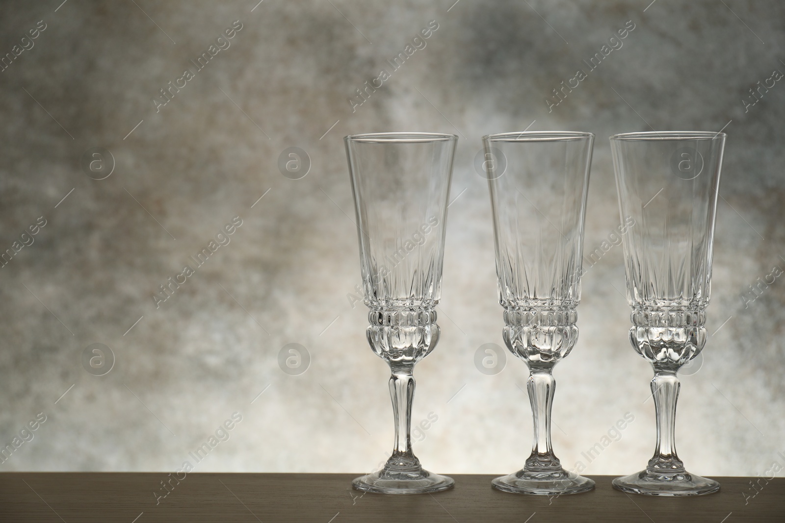 Photo of Three empty clean glasses on wooden table. Space for text