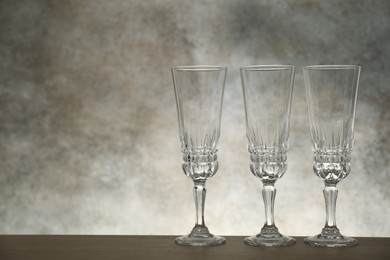 Photo of Three empty clean glasses on wooden table. Space for text