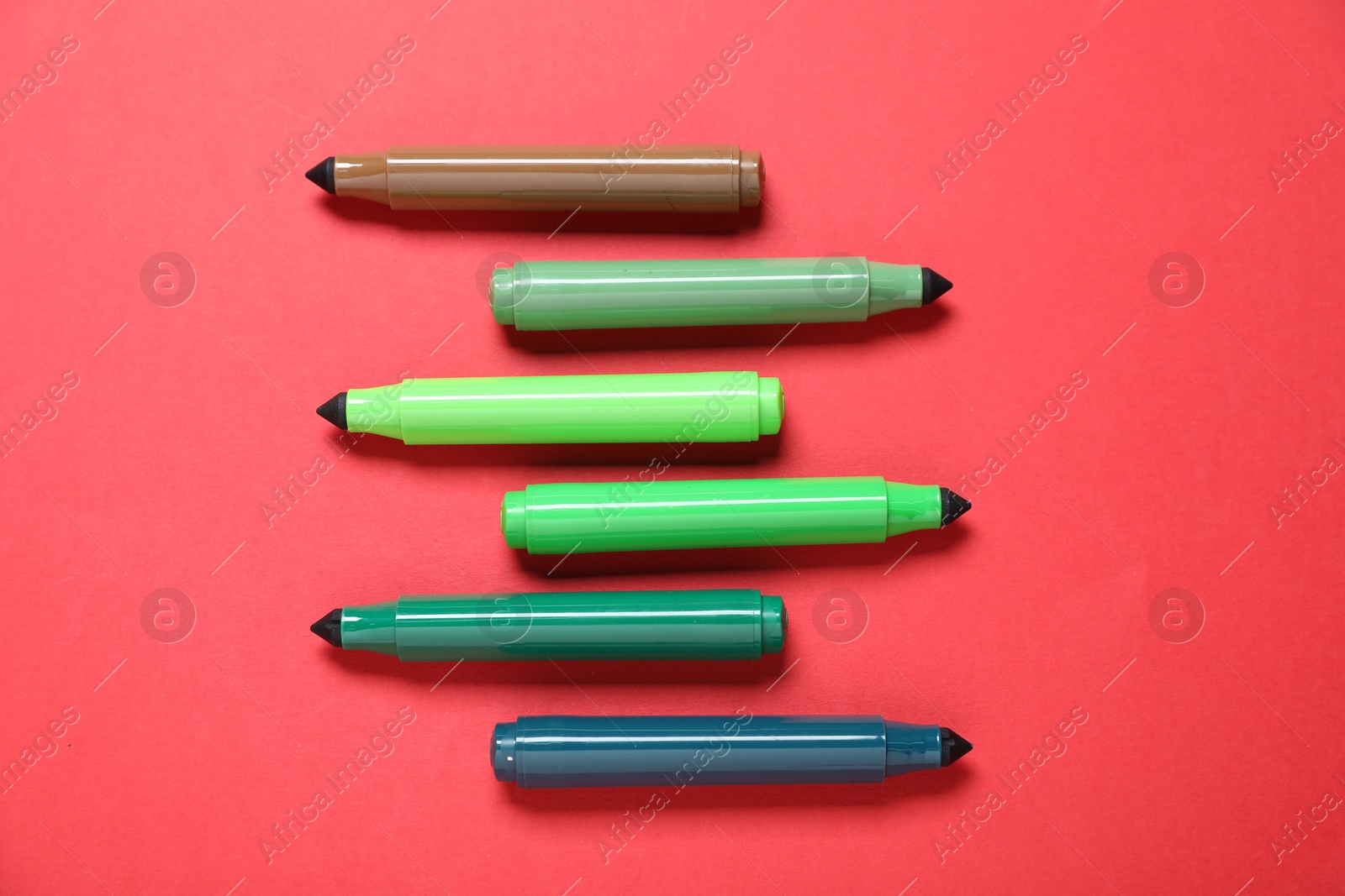 Photo of Many colorful markers on red background, flat lay
