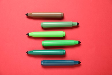 Photo of Many colorful markers on red background, flat lay