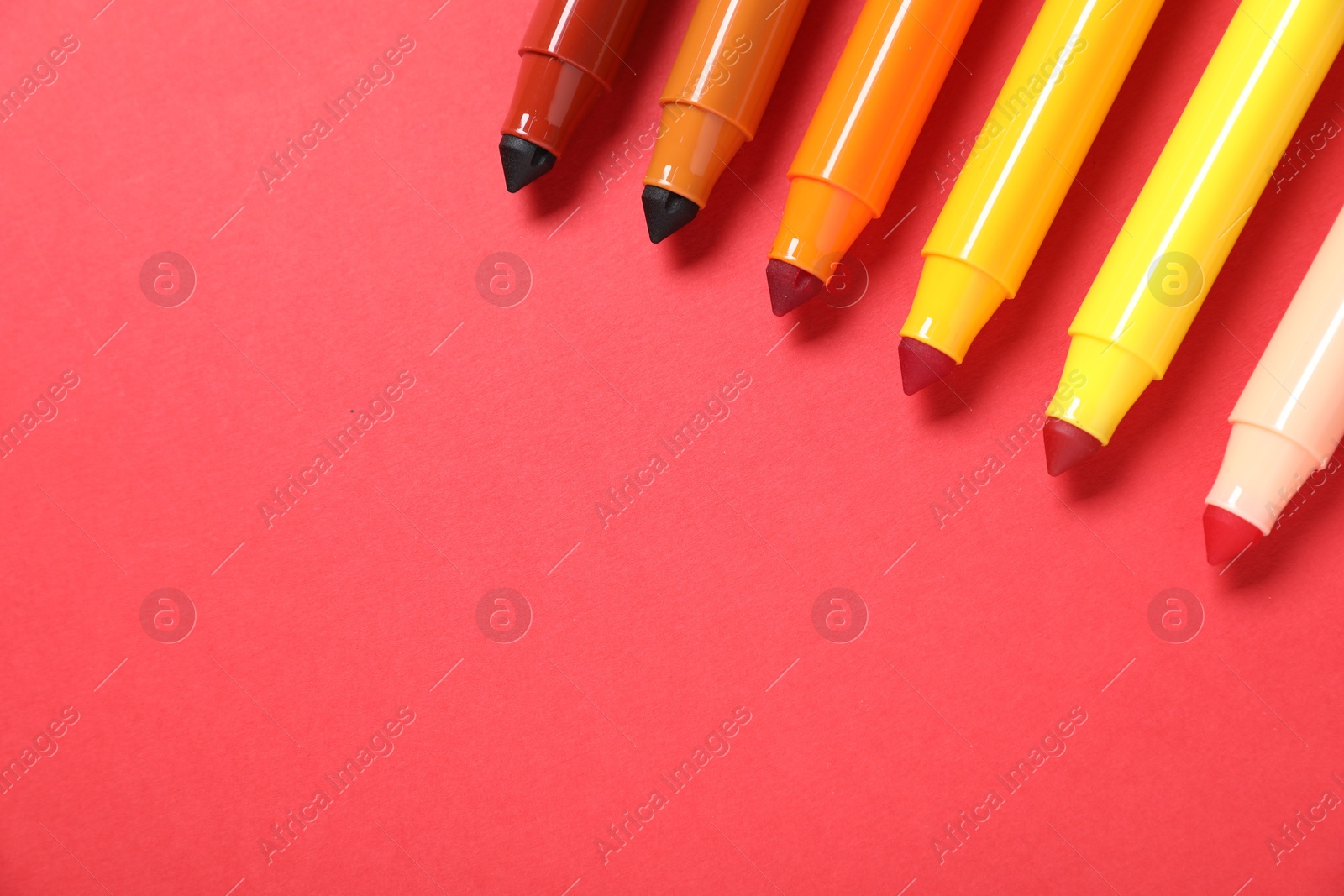 Photo of Many colorful markers on red background, flat lay. Space for text