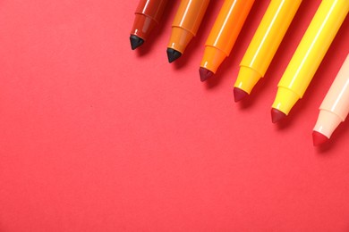 Photo of Many colorful markers on red background, flat lay. Space for text