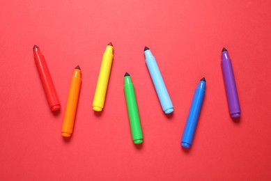Photo of Many colorful markers on red background, flat lay