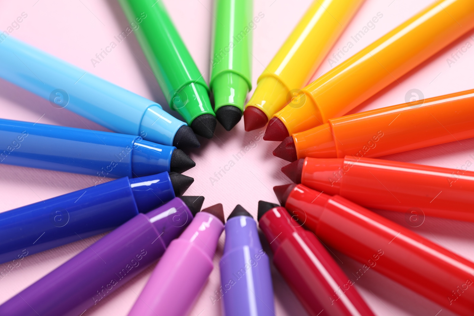 Photo of Many colorful markers on pink background, closeup