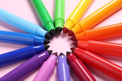 Photo of Many colorful markers on pink background, closeup
