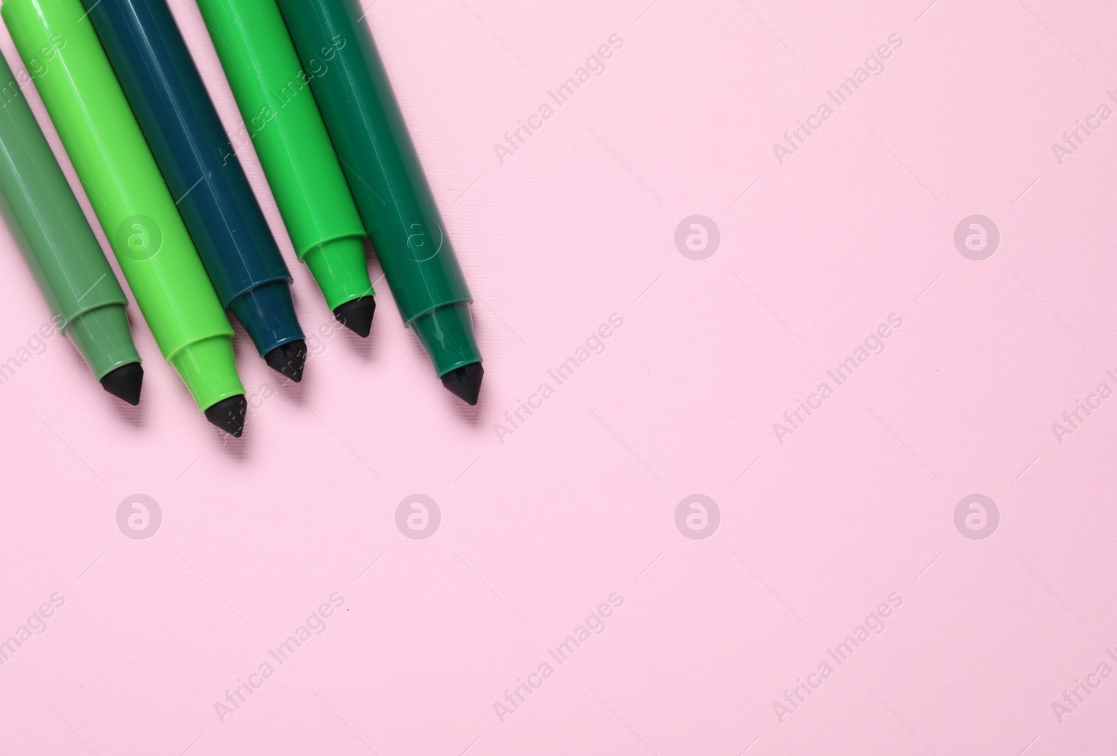 Photo of Many green markers on pink background, flat lay. Space for text