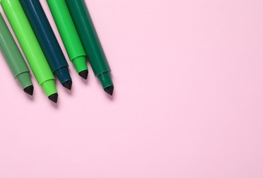 Photo of Many green markers on pink background, flat lay. Space for text