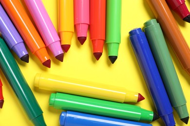 Photo of Many colorful markers on yellow background, flat lay