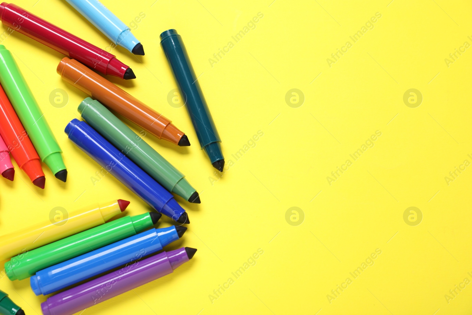 Photo of Many colorful markers on yellow background, flat lay. Space for text