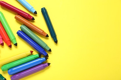 Photo of Many colorful markers on yellow background, flat lay. Space for text