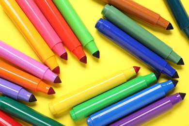 Photo of Many colorful markers on yellow background, flat lay