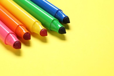 Photo of Many colorful markers on yellow background, closeup. Space for text