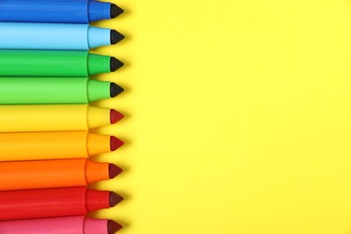 Photo of Many colorful markers on yellow background, flat lay. Space for text