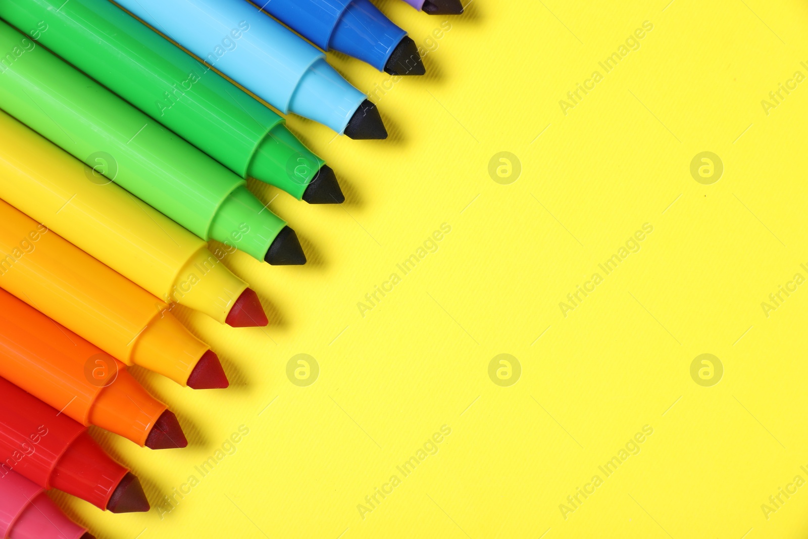 Photo of Many colorful markers on yellow background, flat lay. Space for text
