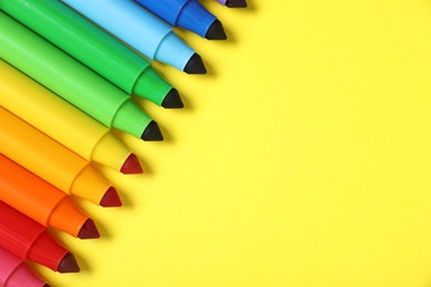 Photo of Many colorful markers on yellow background, flat lay. Space for text