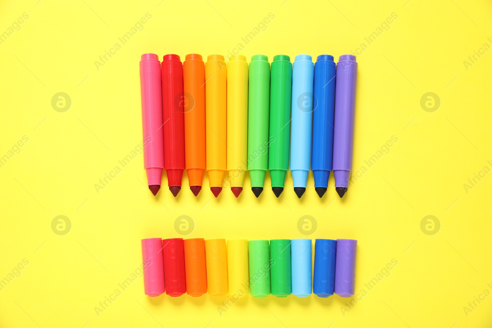 Photo of Many colorful markers on yellow background, flat lay