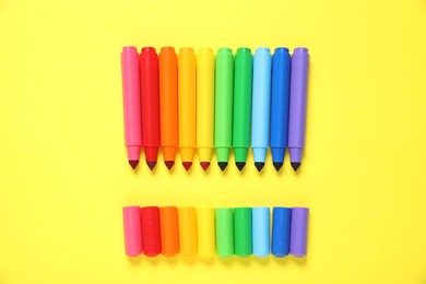 Photo of Many colorful markers on yellow background, flat lay