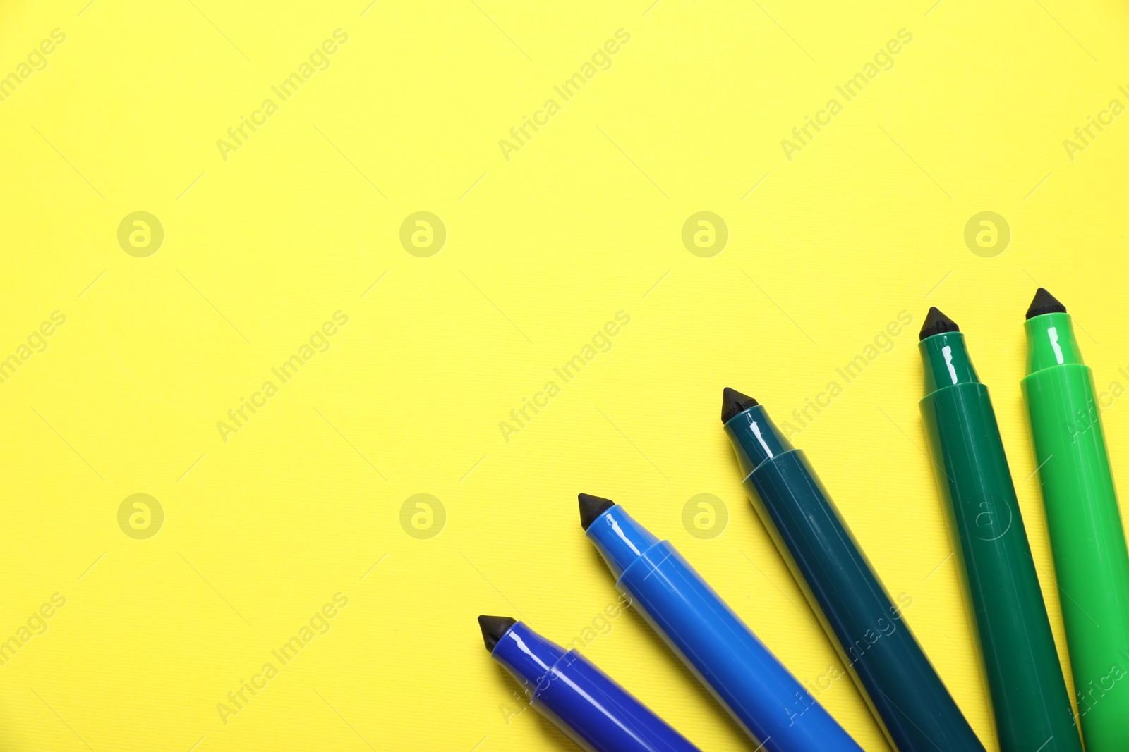 Photo of Many colorful markers on yellow background, flat lay. Space for text