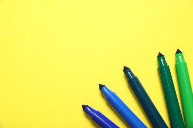 Photo of Many colorful markers on yellow background, flat lay. Space for text