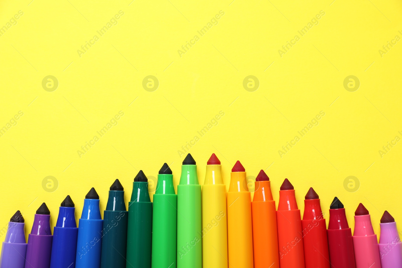 Photo of Many colorful markers on yellow background, flat lay. Space for text
