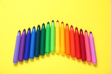 Photo of Many colorful markers on yellow background, flat lay