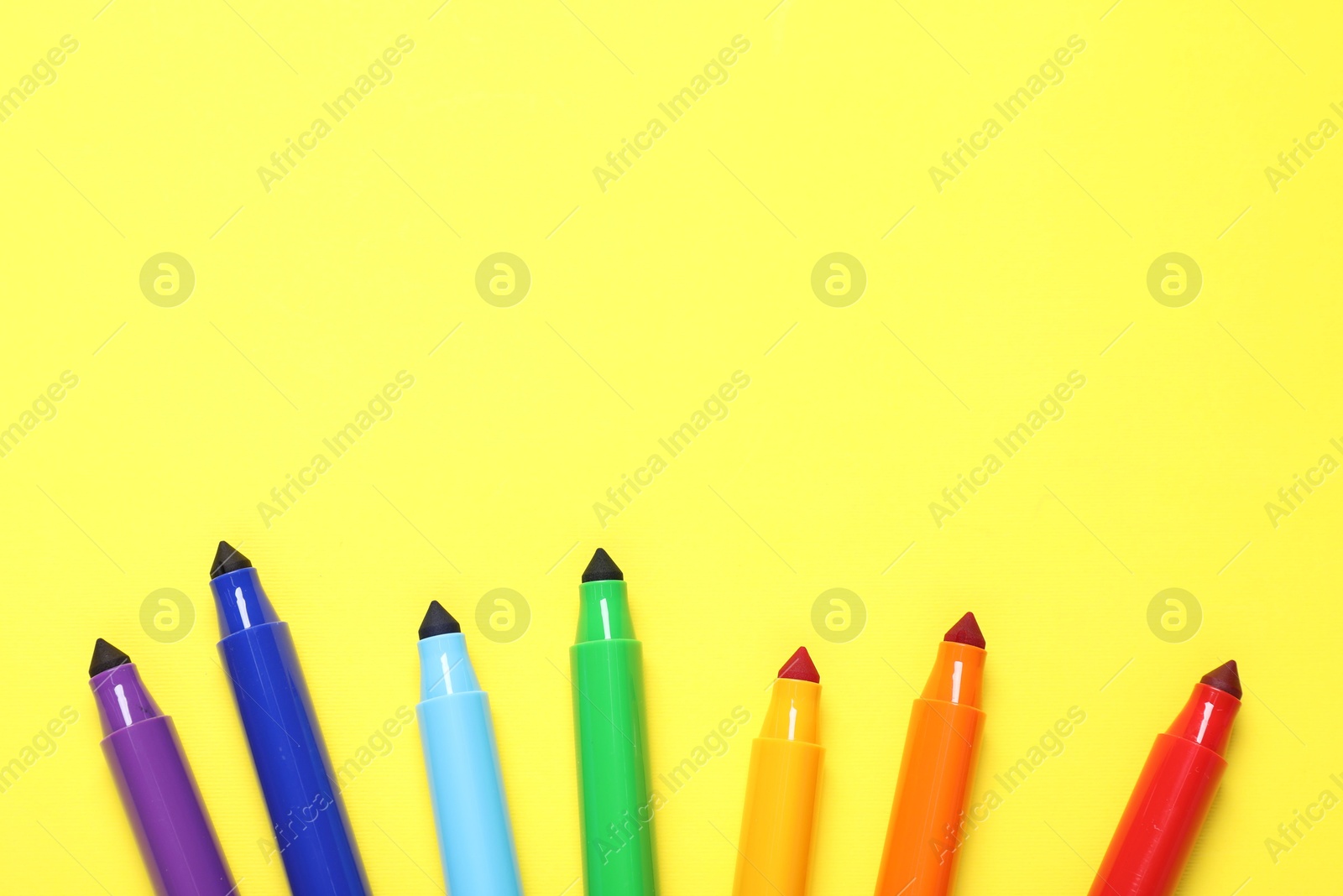 Photo of Many colorful markers on yellow background, flat lay. Space for text