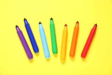Photo of Many colorful markers on yellow background, flat lay