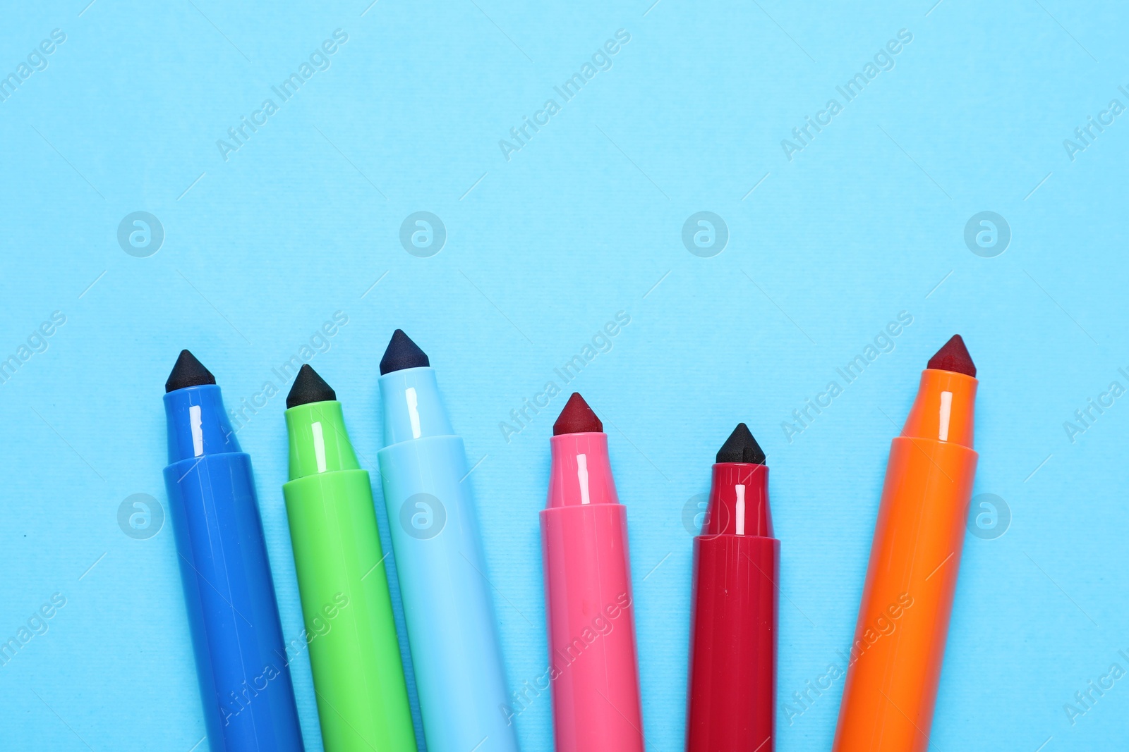 Photo of Many colorful markers on light blue background, flat lay. Space for text
