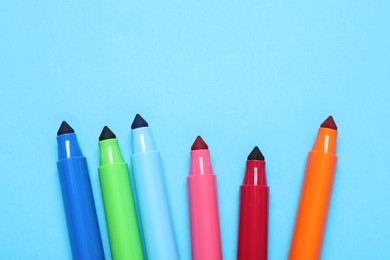 Photo of Many colorful markers on light blue background, flat lay. Space for text