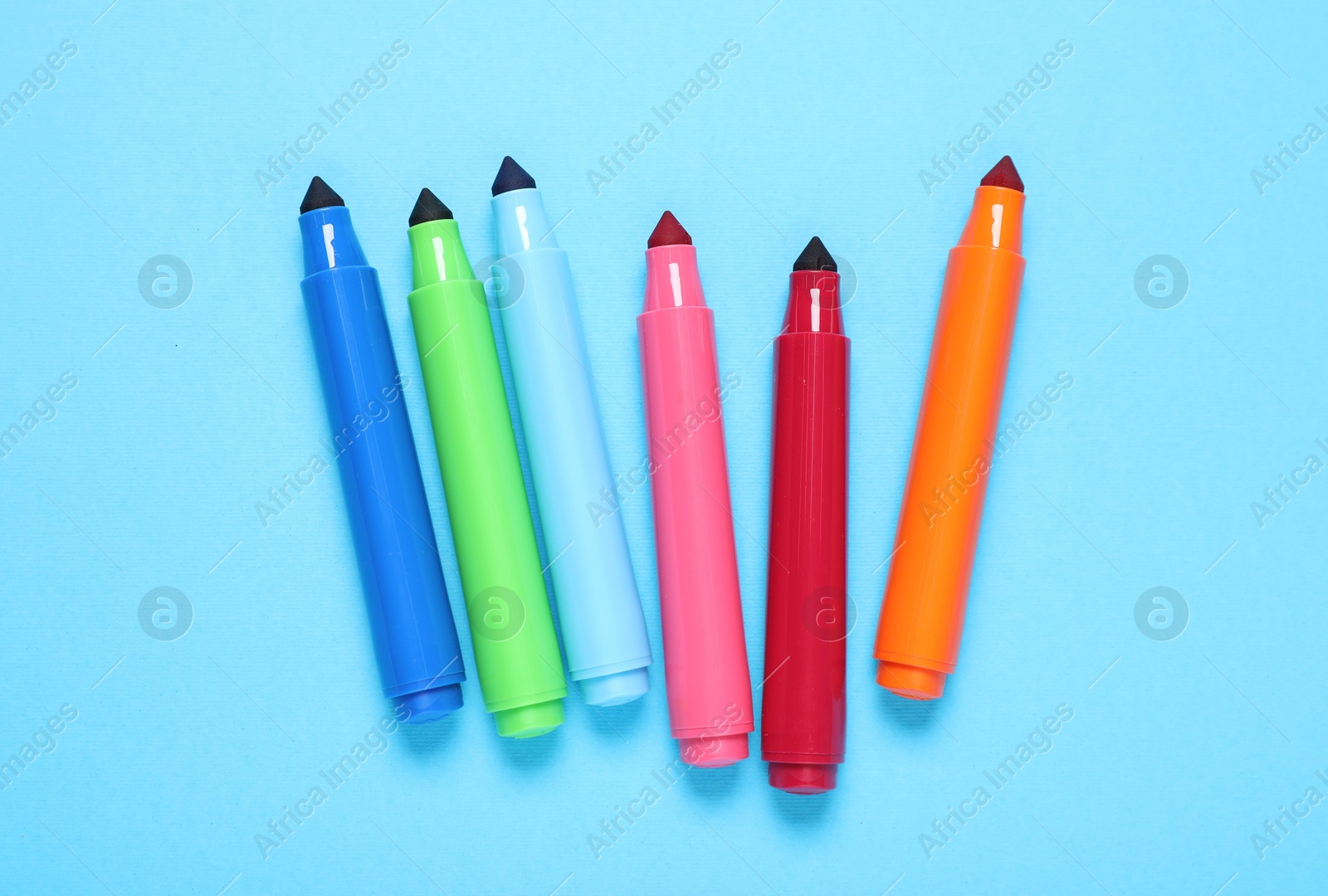 Photo of Many colorful markers on light blue background, flat lay