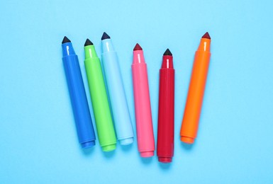 Photo of Many colorful markers on light blue background, flat lay