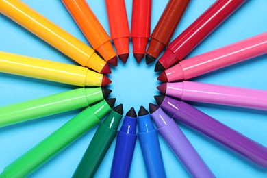 Photo of Many colorful markers on light blue background, flat lay