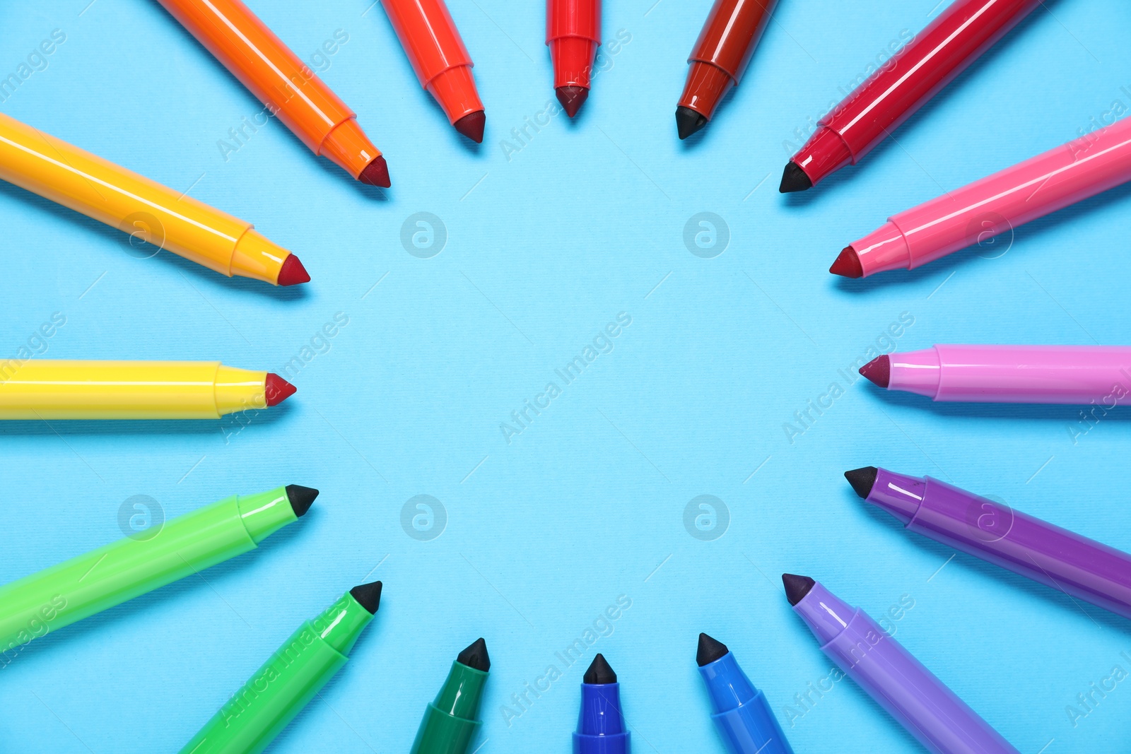 Photo of Frame made of many colorful markers on light blue background, flat lay. Space for text