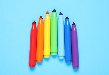 Photo of Many colorful markers on light blue background, flat lay