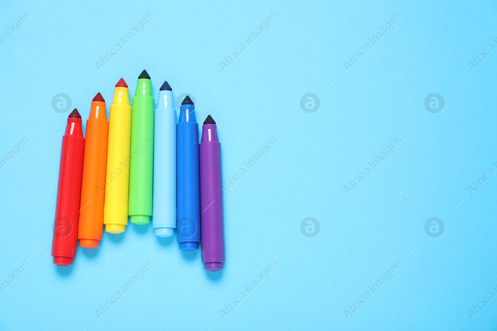 Photo of Many colorful markers on light blue background, flat lay. Space for text