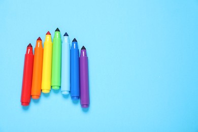 Photo of Many colorful markers on light blue background, flat lay. Space for text