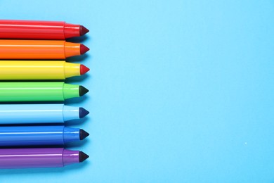 Photo of Many colorful markers on light blue background, flat lay. Space for text