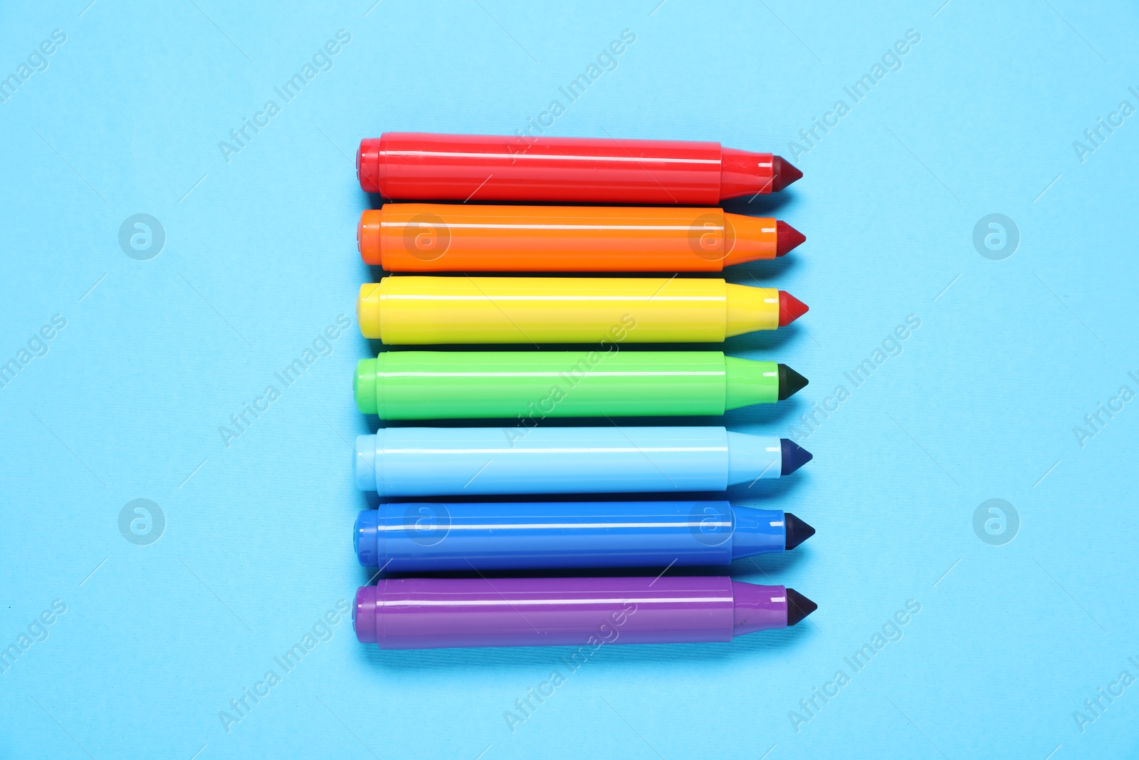 Photo of Many colorful markers on light blue background, flat lay