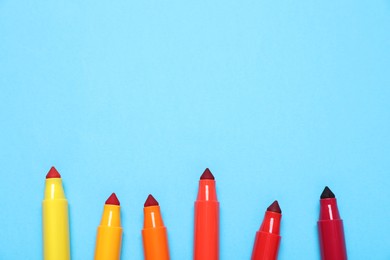 Photo of Many colorful markers on light blue background, flat lay. Space for text