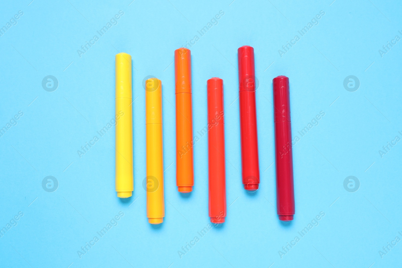 Photo of Many colorful markers on light blue background, flat lay