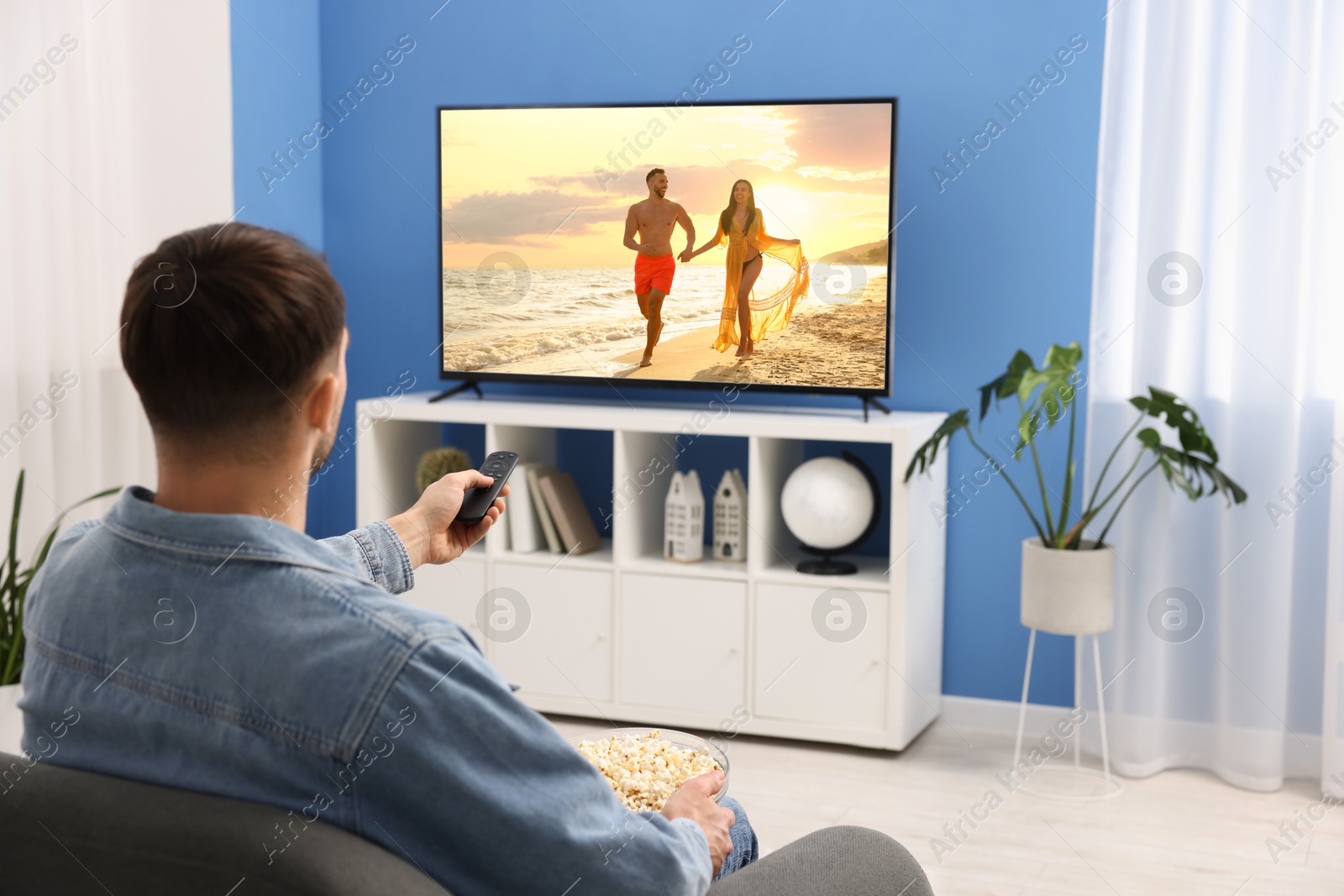 Image of Man watching movie on TV set at home