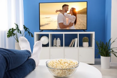 Image of Man watching movie on TV set at home