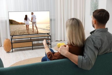 Image of Couple watching movie on TV set at home